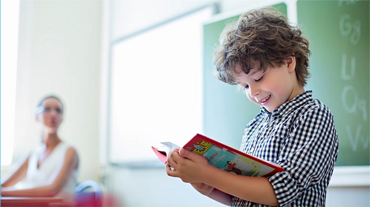 photo enfant lit un livre devant la classe